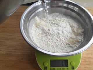 1、烫面葱油饼,水烧开，称好面粉后，直接一边倒入一边过秤，最好烫到所有面粉，这样比较方便操作。一边倒水一边拌匀（我一手拍照，所以不能显示操作过程）