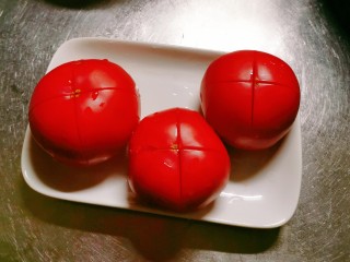 2、番茄黑鱼片,番茄顶端划十字刀 放入开水汆烫 