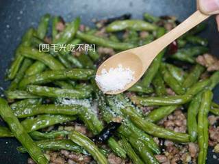 11、干煸四季豆,放入炸好的四季豆，加盐、鸡粉快速炒15至20秒，即可出锅。
