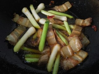 9、回锅肉,先将大蒜茎放入锅内一同翻炒