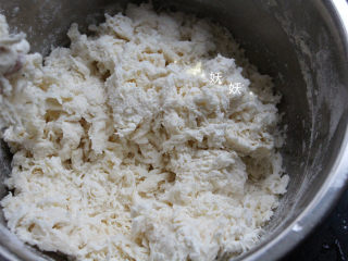 2、葱油烙饼,缓缓加入温水，一边加一边搅拌，面团呈絮状。