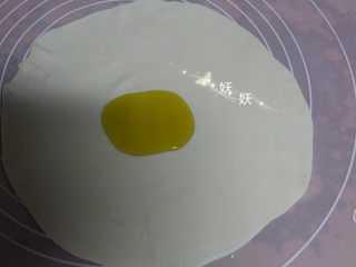 6、葱油烙饼,取其中的一个小剂子，擀成薄薄的片状，形状不规则也没用关系，尽量擀薄就可以了。面皮中间滴上植物油。