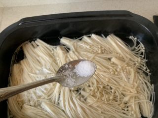 3、酸汤肥牛,料理锅中烧水,加一点盐,水开倒入金针菇烫熟。