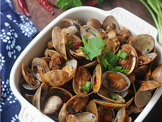 12、炒花蛤,将香菜末、葱花撒入锅中翻炒均匀即可