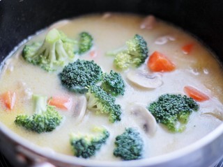 11、承味＃延世牛奶炖菜,把白酱倒入盛有食材的汤锅中搅拌均匀，加入西兰花煮两分钟