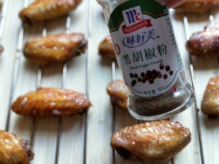 12、孜然烤鸡翅#烤箱版#,10分钟后戴上隔热手套取出烤网，再鸡翅上刷一层食用油，再撒上胡椒粉。