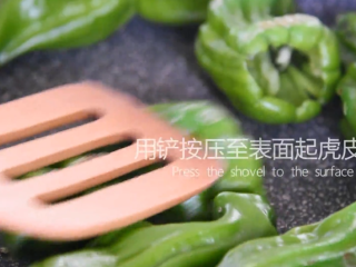 4、“虎皮青椒”美味又下饭，上桌分分钟变光盘,热锅下青椒，并用铲按压表面