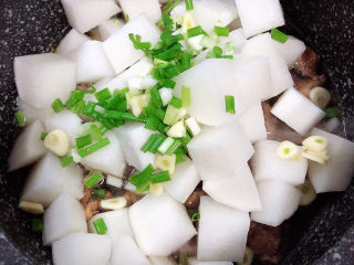 14、萝卜牛腩煲,放入葱蒜，搅拌均匀。