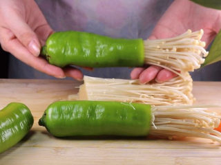 7、往青椒里塞入半斤金针菇，这味道绝了！,取一小把金针菇，将金针菇塞入青椒里，多余的空间我们可以借助胡萝卜条来填充，让连接处紧实，这样金针菇就不容易滑落了。