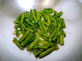 9、干煸四季豆,倒入四季豆,用铲子炒均匀后铺平,为了使每个四季豆均匀受热。
