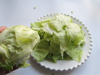 2、腊肉蒜香卷心菜,将包菜手撕成一个个大片，厚的根部去掉