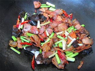 7、腊肉蒜香卷心菜,放入蒜段、木耳、生姜、红干椒、花椒翻炒几秒钟