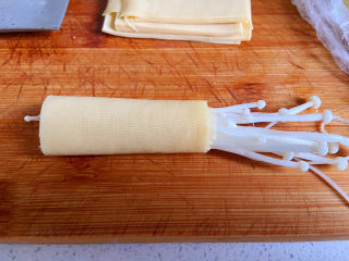 3、豆皮金针菇卷,用豆皮包住金针菇，再用牙签固定。