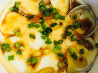 23、花蛤蒸蛋,时间到了，取出并撕开保鲜膜，淋上香油和生抽，最后撒上葱花即可