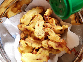 15、椒盐里脊,捞出的里脊放入盆中,吸油纸吸去多余的油脂,撒上椒盐,垫几下让里脊上粘匀椒盐粉即可。