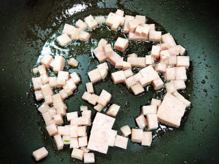 7、青菜炒饭,锅中倒入油，加热至五成热，放入午餐肉丁翻炒均匀。