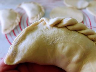 8、韭菜盒子,面饼的一侧对折，捏紧封口，如图，捏出花纹。