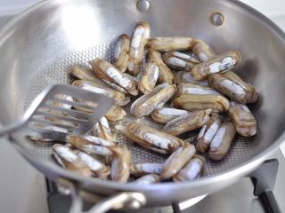 4、韭菜炒蛏子,等蛏子张开口，有汁水淌出时调入精盐翻炒均匀。