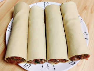 10、千张包肉,将豆皮肉卷从中间切开放入盘中。