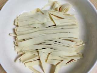 2、韭菜炒千张,将豆皮切成细长条,放入碗中。