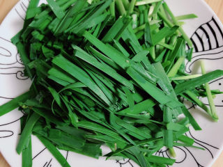 4、韭菜炒千张,将韭菜切成小段儿,放入盘中。