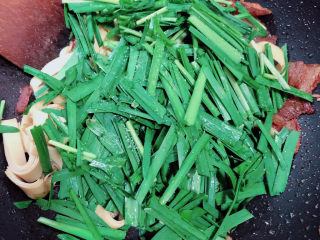 12、韭菜炒千张,加入韭菜,继续翻炒。