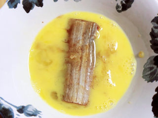 8、炸酥带鱼,带鱼腌好后，取一块放入蛋液中，裹上蛋液。