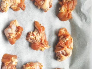 4、比外卖还好吃的秘制烤翅根,在烤盘上铺一张干净的油纸，把腌制好的翅根均匀的放在烤盘上。