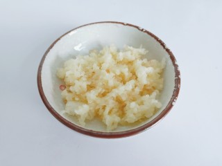 2、蒜香鸡翅,用刀背把蒜拍扁,剥去蒜壳放压蒜器压碎或者用刀剁碎。