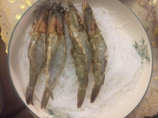 6、花开富贵粉丝蒜蓉虾,把粉丝泡开铺在碗里，上面放入开好背的虾。
