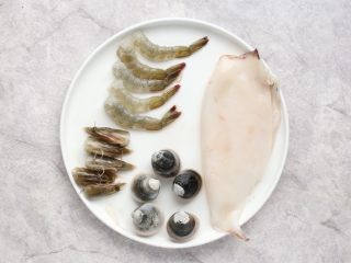 3、海鲜咖喱乌冬面,大虾去头、去壳、去虾线，虾尾的壳保留，虾头留用，将虾上的黏液冲洗干净；鱿鱼去内脏撕去外膜洗净，将鱿鱼筒对半剪开；文蛤选吐净泥沙的，冲洗干净。