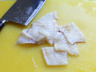 4、海鲜咖喱乌冬面,刀倾斜着在鱿鱼筒内壁表面划刀，间隔匀均，然后交叉再划一遍，接着改刀切小块。