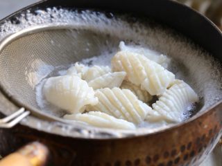 5、海鲜咖喱乌冬面,准备一锅清水，加入二片姜烧开，将切好的鱿鱼放入沸水中焯至卷曲变白捞出，焯鱿鱼的水留用。