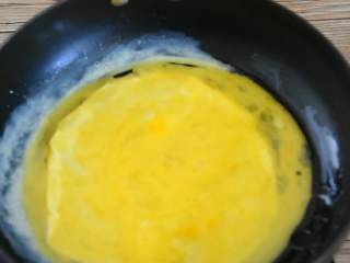 4、抱蛋千张卷—看世界杯没有宵夜怎么行,热锅刷少许油，小火倒入一半蛋液，轻轻推开。