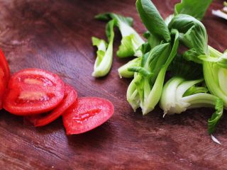 11、排骨青菜番茄面,把番茄用刀切成薄片，青菜用刀切开。