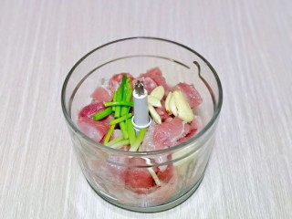 4、芥菜饺子,将肉块放入绞肉机中，再加入葱姜蒜。