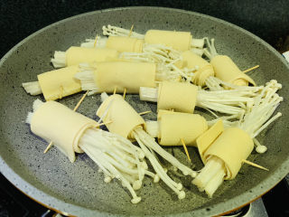 7、豆皮金针菇卷,锅加食用油，大火热锅，转小火，下豆皮金针菇卷