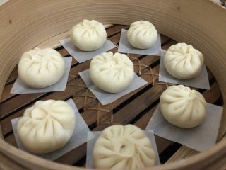 21、梅干菜肉包,蒸笼里放入纸垫，把包好的包子放进去盖盖，等它第二发酵，怎么确定它有没有发好，手指按一下有蓬松的感觉就可以了，（明显是比刚包的时候大半倍）