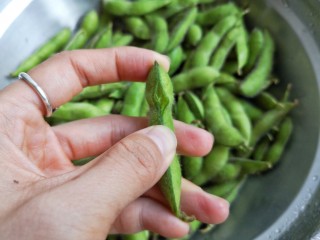 3、香辣毛豆,为了让毛豆在煮的过程中更入味，建议将洗净的毛豆皮挤开一个小口。