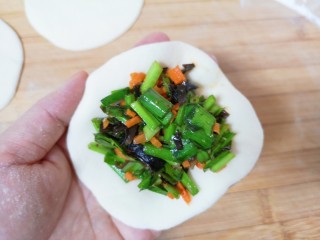 12、胡萝卜韭菜馅包子,取一个包子皮拿在手上，放上足够多的包子馅。