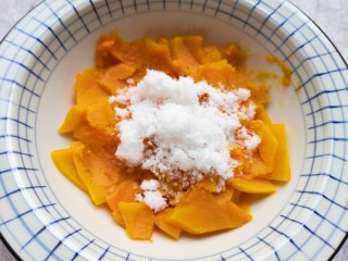 3、南瓜芝麻球,蒸熟的南瓜片从蒸锅里取出，放进大一点的碗里，加入纯牛奶和绵白糖。