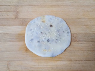 8、梅干菜烧饼,收口朝下，撒上少许熟白芝麻，用擀面杖擀成薄饼，依次做好剩下的面团。 烤箱上下管200度预热。 