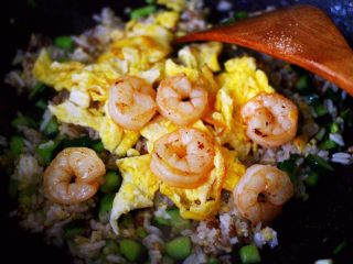 12、黄瓜虾仁杂粮蛋炒饭,翻炒均匀的杂粮米饭后，倒入炒熟的鸡蛋和虾仁。