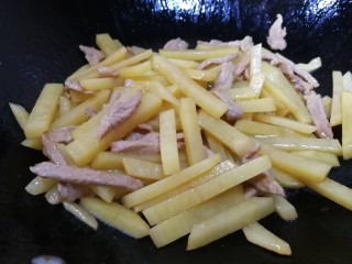 11、土豆炒肉丝,放入姜丝和土豆条文火翻炒1分钟，把土豆条炒透明。