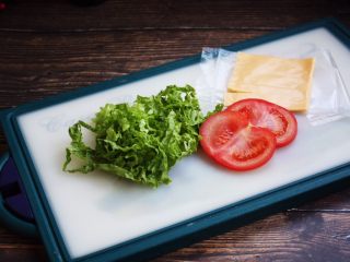 2、三明治,生菜切丝，切两片番茄片，番茄片切的稍稍薄些，芝士片从冰箱冷藏室拿出来，将包装轻轻撕开。