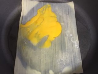 3、烤冷面,放入一个鸡蛋，用铲子拍开，均匀的涂抹在冷面上