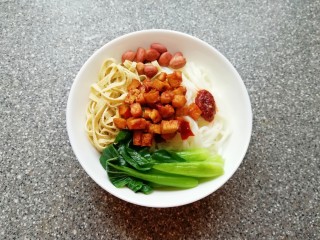 9、骨汤米线, 取一个碗,放入煮好的米线,依次放入青菜、豆腐皮、花生米和炒好的豆腐干,根据自己的口味放盐和鸡精(喜欢吃辣椒的可以放一些辣椒)。