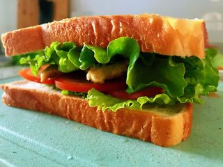 5、鸡胸肉三明治,拿出一片吐司面包片,放一层生菜,再放一层西红柿片,放入鸡胸肉,上面再放入一层西红柿片,再放入一层生菜,最上面继续放入一层面包片,这样所有的食材就全部放完了?当然,如果有别的喜欢吃的也可以放入,比如说黄瓜,紫甘蓝,对蔬菜的搭配,可以按照自己的口味儿灵活变动。