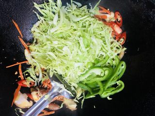 16、卷心菜炒粉丝,放入卷心菜和青椒翻炒均匀