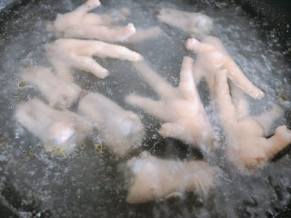 4、虎皮鸡爪,锅内烧开水，加入姜片和料酒，把鸡爪放入水中煮15分钟，除去浮末。
